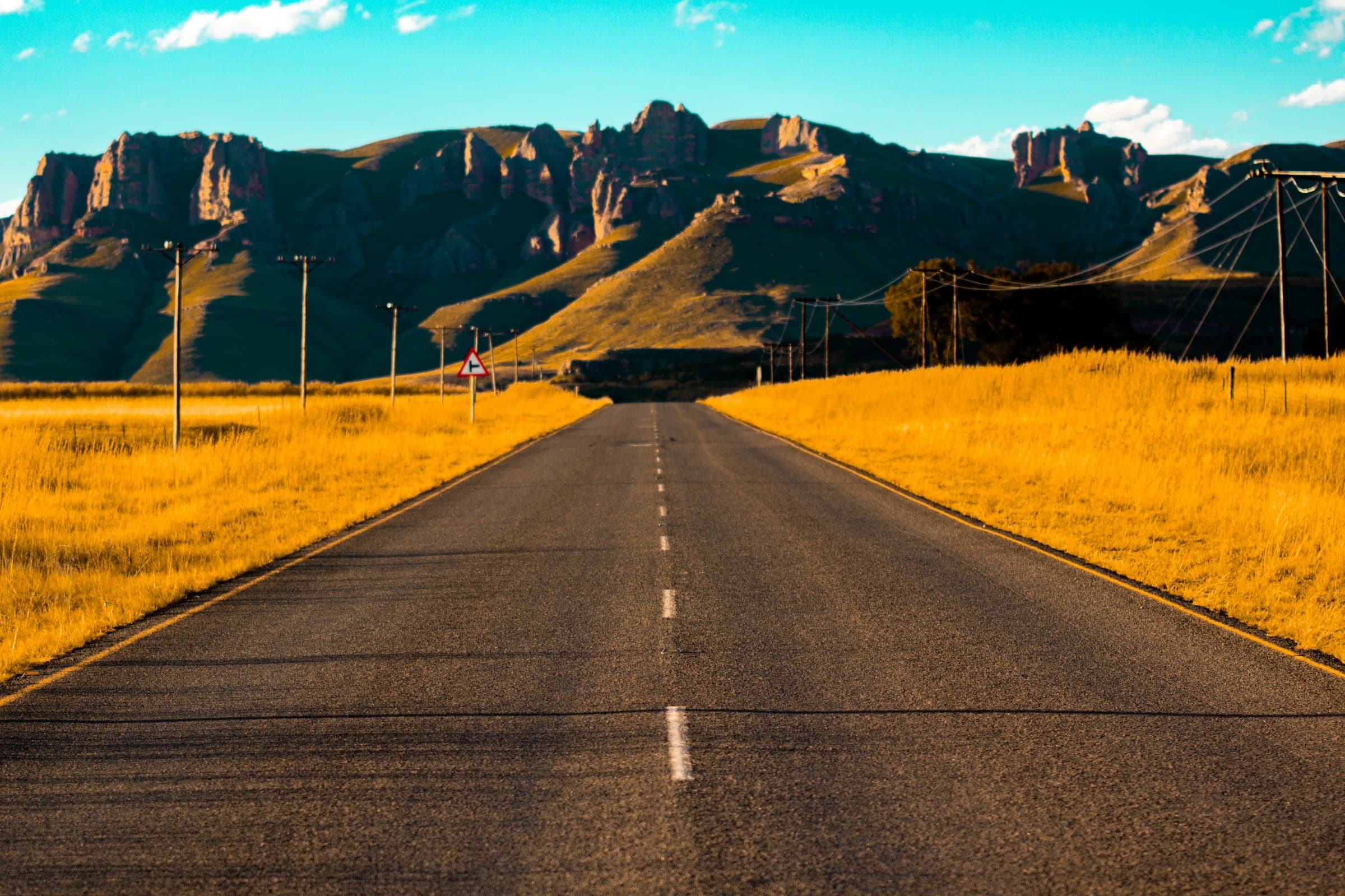 A long straight road running toward a mountain range